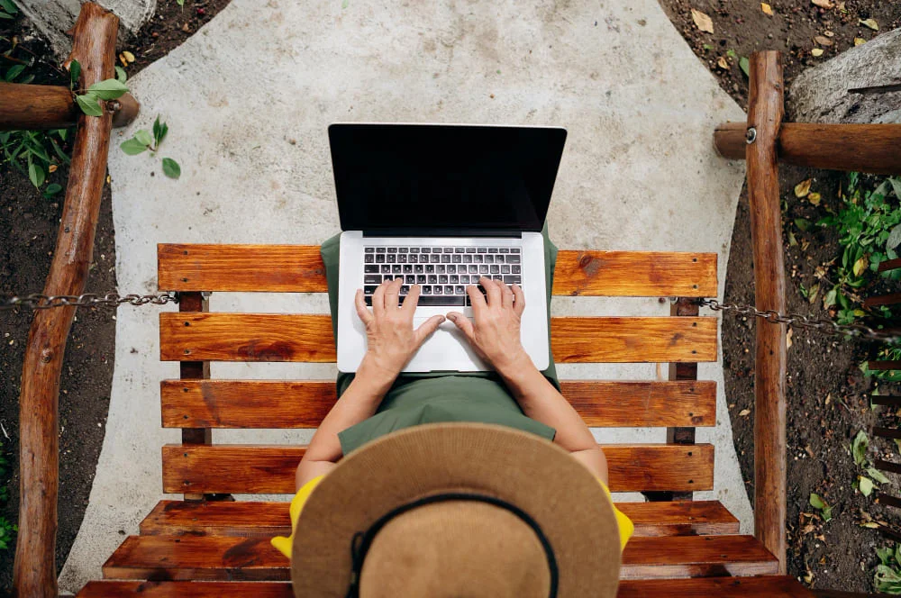 Mujer escribiendo en portátil trabajando como nómada digital